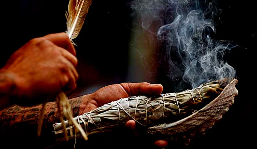 A person holding a feather and smoke in their hands.